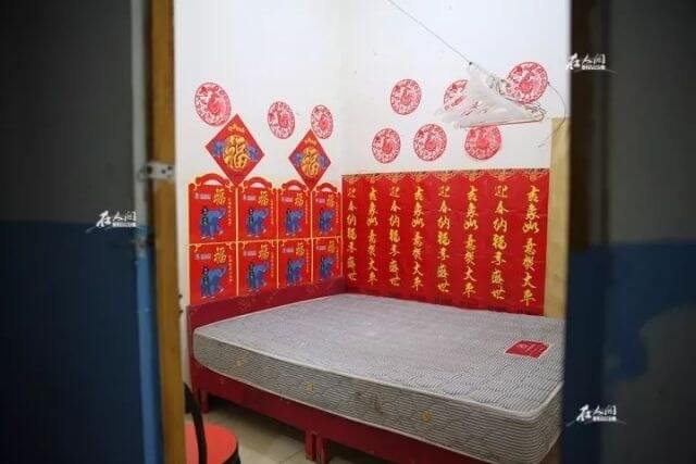 一间早已没人的房间，整面墙壁贴满了对联：“迎春纳福享盛世，吉祥如意贺太平